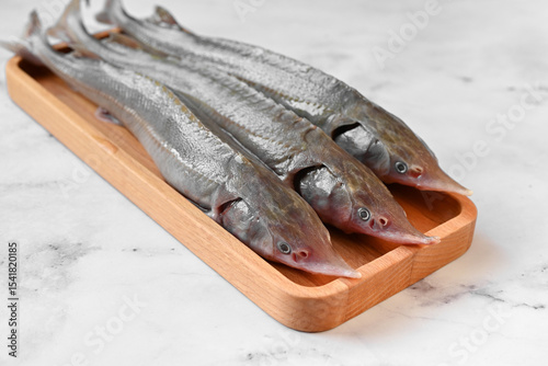 Raw sterlet fish on a wooden plate with pepper