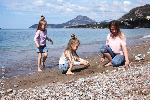 mother with twins daughters on beach