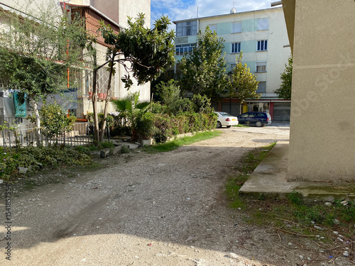 Urban landscape: houses, road, power lines and green vegetation in a small Albanian town. Local life, traditional buildings, street view concept. Illustrative photo for your design or article.