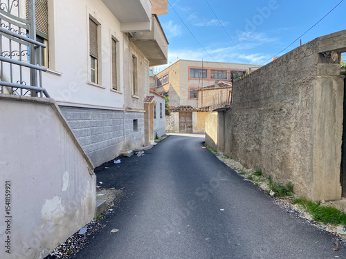 Residential view of rural Albania showing modest homes, electric cables, and greenery creeping through cracks. A peaceful and authentic moment perfect for editorial or travel use.