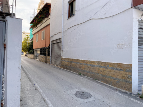 Everyday scene from Albania: quiet road, small homes, electrical wires, and bushes. Realistic and grounded image for blogs, articles, or regional design projects.