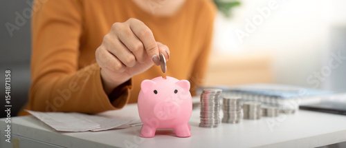 Savings and Financial Responsibility. Woman depositing coins into a piggy bank. photo