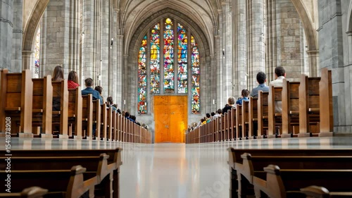 Interior of a grand cathedral with stained glass windows and wooden pews filled with people. Spiritual atmosphere, religious gathering, prayer, and architectural heritage concept