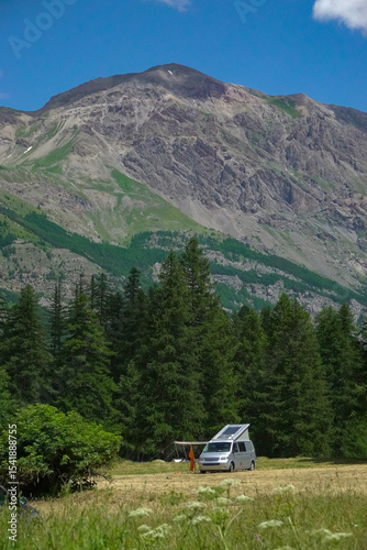 Fotografie Silver camper van set up on a grassy field, nestled at the base of a majestic, rugged mountain