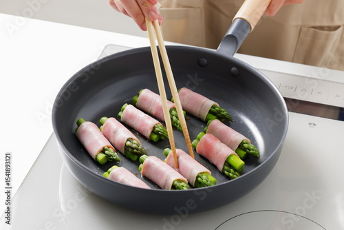 フライパンでアスパラベーコンを焼く料理のシーン　Asparagus Bacon Being Cooked in a Frying Pan