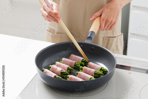 フライパンでアスパラベーコンを焼く料理のシーン　Asparagus Bacon Being Cooked in a Frying Pan