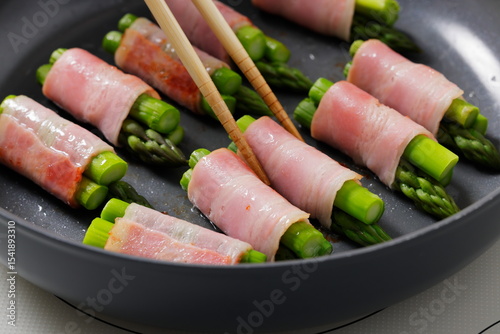 フライパンでアスパラベーコンを焼く料理のシーン　Asparagus Bacon Being Cooked in a Frying Pan