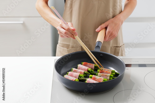 フライパンでアスパラベーコンを焼く料理のシーン　Asparagus Bacon Being Cooked in a Frying Pan