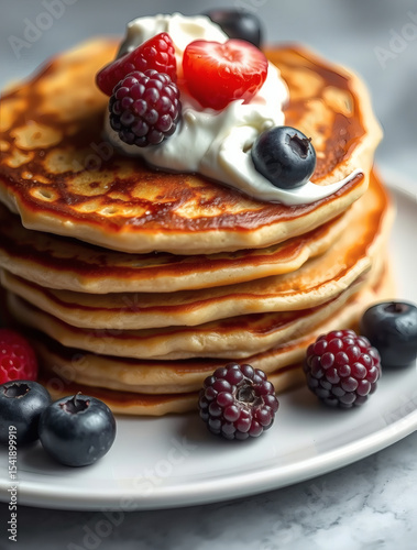 Delicious stack of fluffy pancakes topped with fresh berries and whipped cream on a marble table