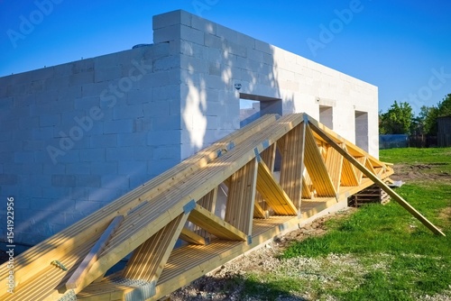 Wooden Roof Trusses at Modern House Construction Site. Prefabricated Roof Trusses on Ground Before Installation.