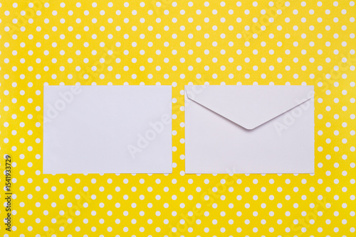 Two white envelopes on a yellow with white polka dots background with copy space