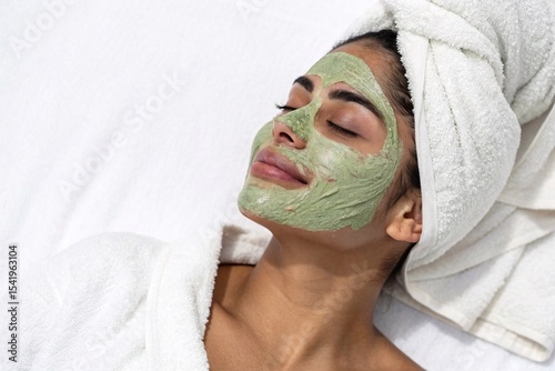 Smiling woman with green face mask at spa
Relaxed woman in a bathrobe and towel wrap enjoying a skincare routine with a green facial mask, promoting beauty and wellness.
