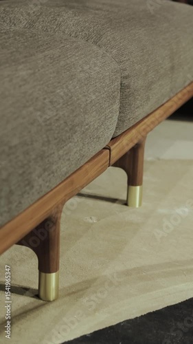 Vertical video. A modern sofa, with gray frame and wooden legs and gold elements, which perfectly demonstrates the perfect combination of comfort and aesthetics of modern design
