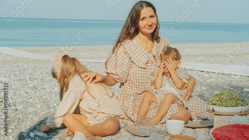 Wallpaper Mural Young mother with children having a summer picnic by the sea, enjoying family time on the beach with fruit and sunshine. Torontodigital.ca