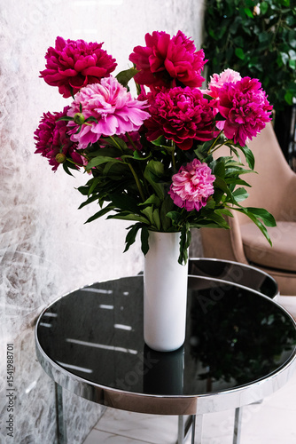 A bouquet of peonies in a vase on the table, no peole.