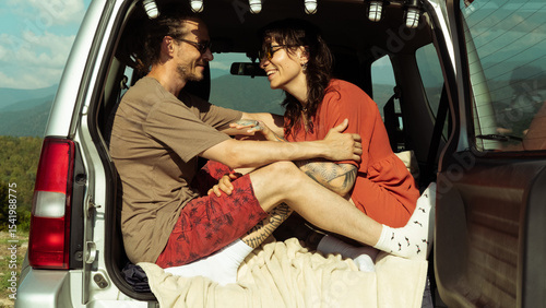 Wallpaper Mural Happy couple relaxing in car trunk during road trip. Smiling and enjoying mountain view and adventure moment together. Torontodigital.ca