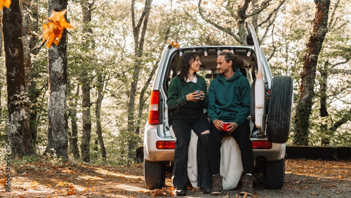 Wallpaper Mural Young couple sitting in trunk, drinking hot beverages and enjoying peaceful autumn forest together Torontodigital.ca