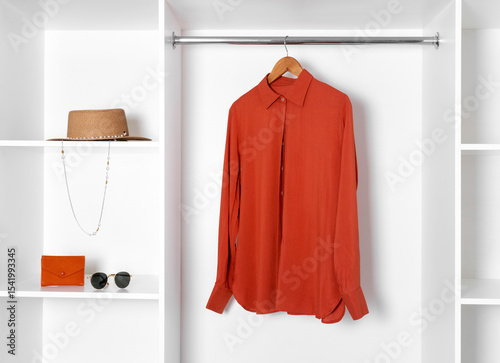 Wallpaper Mural Minimalist closet with terracotta shirt on hanger and stylish accessories on shelves — sunglasses, hat, wallet. Elegant wardrobe organization. Torontodigital.ca