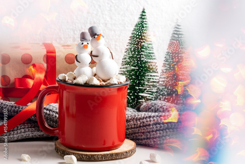 Wallpaper Mural Hot chocolate with marshmallows and cute snowmen in a red mug. Cozy Christmas setup with gift, knit scarf, and holiday trees. Torontodigital.ca