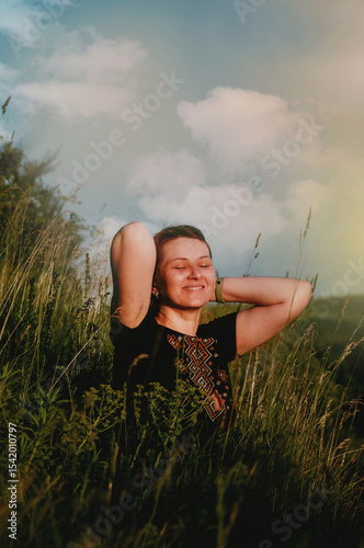 Happy girl with closed eyes and smile in mountains in embroidered shirt