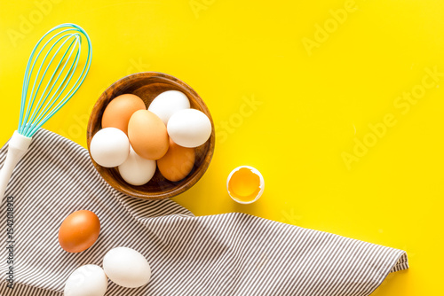 Chicken eggs in wooden bowl on cooking table, top view. Food pattern. Easter background