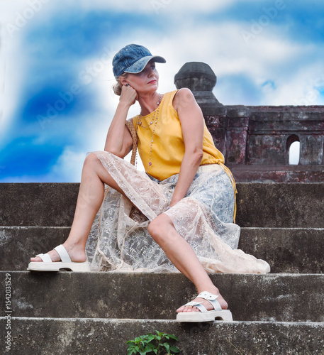A woman sits on ancient ruins in Nha Trang, Vietnam - a moment of silence amidst the historical heritage and nature of Southeast Asia. Tourism concept