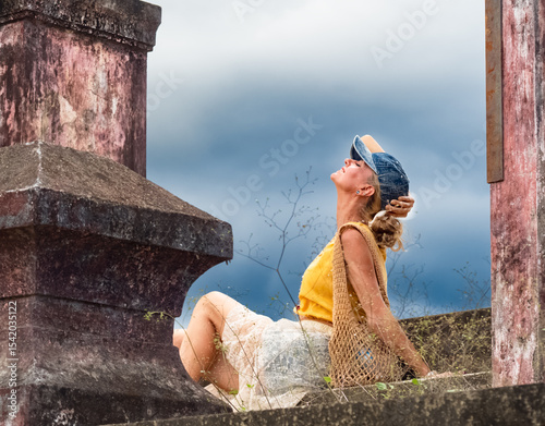 A woman sits on ancient ruins in Nha Trang, Vietnam - a moment of silence amidst the historical heritage and nature of Southeast Asia. Tourism concept