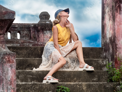 A woman sits on ancient ruins in Nha Trang, Vietnam - a moment of silence amidst the historical heritage and nature of Southeast Asia. Tourism concept