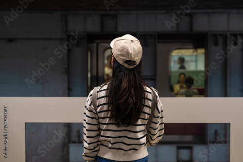 Back view of young female traveler stand on platform waiting subway train in underground station or ready activity and relaxing enjoy life vacation.