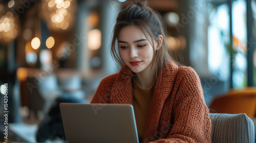 a confident woman typing on laptop in a hotel lobby