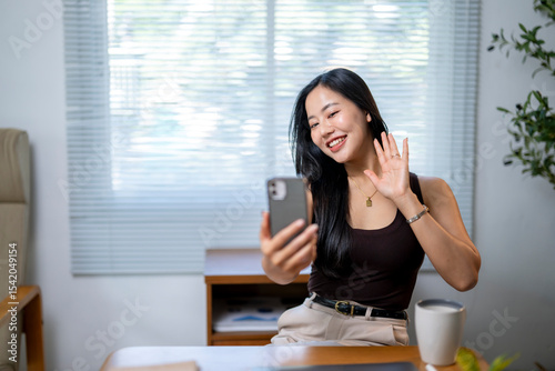 A woman is sitting at a desk with a cell phone in her hand