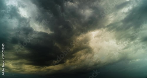 Timelapse of evening sky with impressive storm clouds illuminated by combination of greyish and yellow hues with dark blue in the background and with dramatic atmosphere