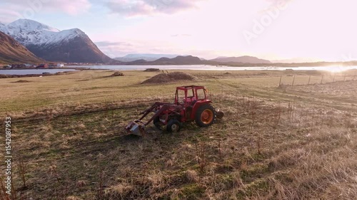 A tractor is working diligently on a beautiful and scenic farm landscape during sunset hours,