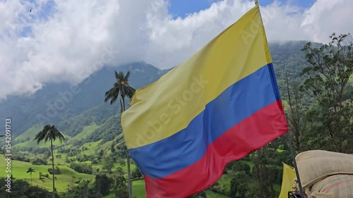 Colombian flag waving in the wind at Valle del Cocora, Salento, with iconic wax palms, lush green vegetation, mountain landscape, national pride, and natural beauty of rural Colombia on display