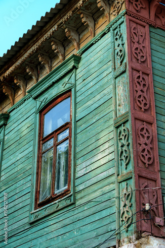 facade of an old building with window, wooden walls and windows painted with weathered green and brown paint, old architecture