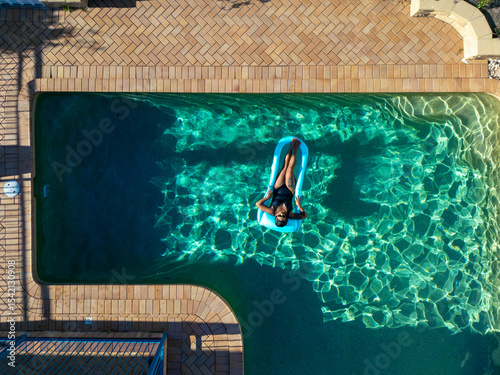 Woman relaxing on inflatable in sunlit swimming pool