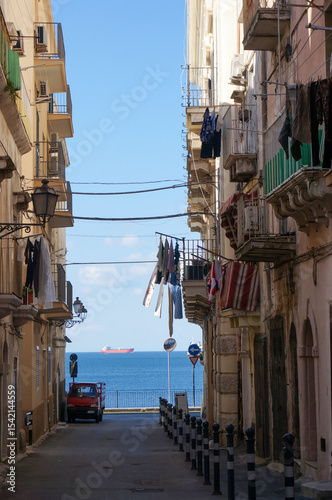Fototapeta Naklejka Na Ścianę i Meble -  Small street in Old Town leads to sea. Taranto, Italy.