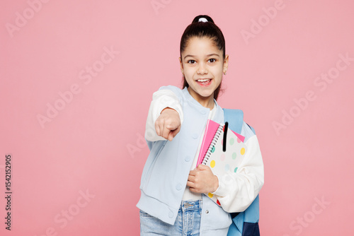 Young happy school girl 8-9 year old wear blue casual clothes backpack point index finger camera on you isolated on plain pink background children portrait. Childhood kids education lifestyle concept photo