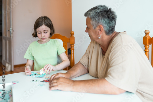 Grandmother and granddaughter doing puzzle at home.