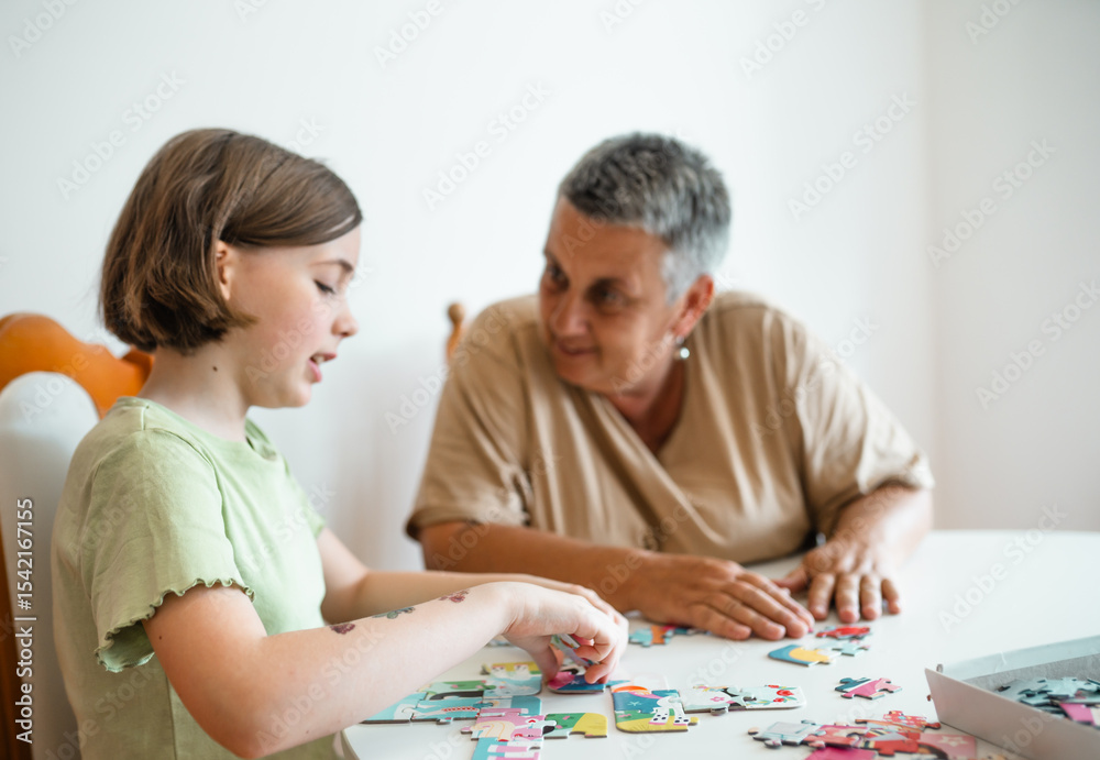 Grandmother and granddaughter doing puzzle at home. Grandmother and granddaughter doing puzzle at home.