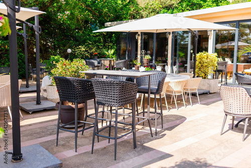 Outdoor cafe terrace with modern wicker furniture. Hospitality setup, summer leisure, and garden dining in a Mediterranean setting.