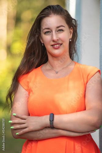 Portrait of a young beautiful girl in an orange dress in a summer forest.
