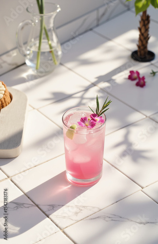 Pink iced drink with flowers on white tiled surface