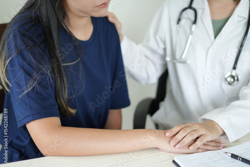 An asian psychiatrist or healthcare professional female doctor is gently holding patient hand comforting and encouragement, reassuring woman, only hands close up. Mental health care support concept.