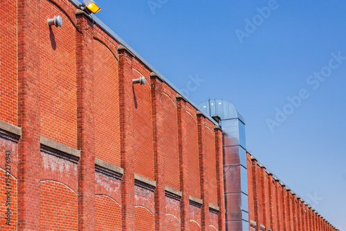 Low angle side view of old industrial building red brick wall against bright blue sky, Sherbrooke, Quebec, Canada