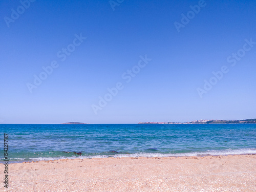 Beach, sea, empty sky and island in the distance