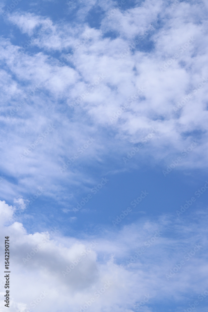 Naklejka premium White clouds against the blue sky. Sky background. Summer. Landscape. Soft white clouds against the blue sky. Calm and serene atmosphere. White fluffy clouds