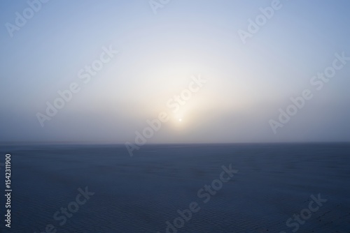Serene sunrise over a misty flatland landscape, showcasing a tranquil dawn scene with soft light and subtle colors ideal for peaceful backgrounds.