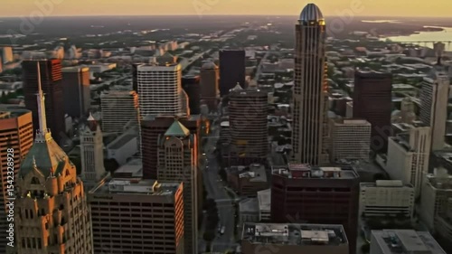 Aerial view of a cityscape at sunset, featuring tall buildings, bridges, and a warm, golden sky