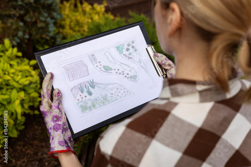 landscape design. woman gardener looking at home backyard garden plan